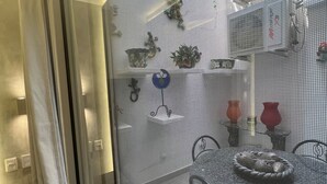 A dining area with a round table and chairs, a decorative plant, and a wall-mounted light fixture. - Heart of Zona Romantica! 2BD/2Baths, 10 Sec. Walk Beach & Malecon! Quiet Street. (Puerto Vallarta)