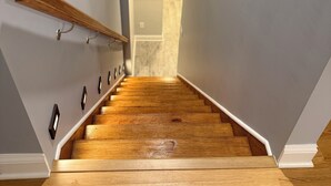 Una escalera de madera con barandilla que lleva a una puerta en la parte superior.