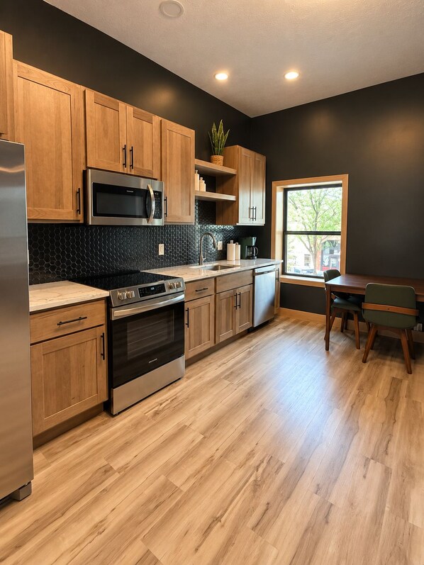 A modern kitchen with wooden cabinets, stainless steel appliances, and a window providing natural light.