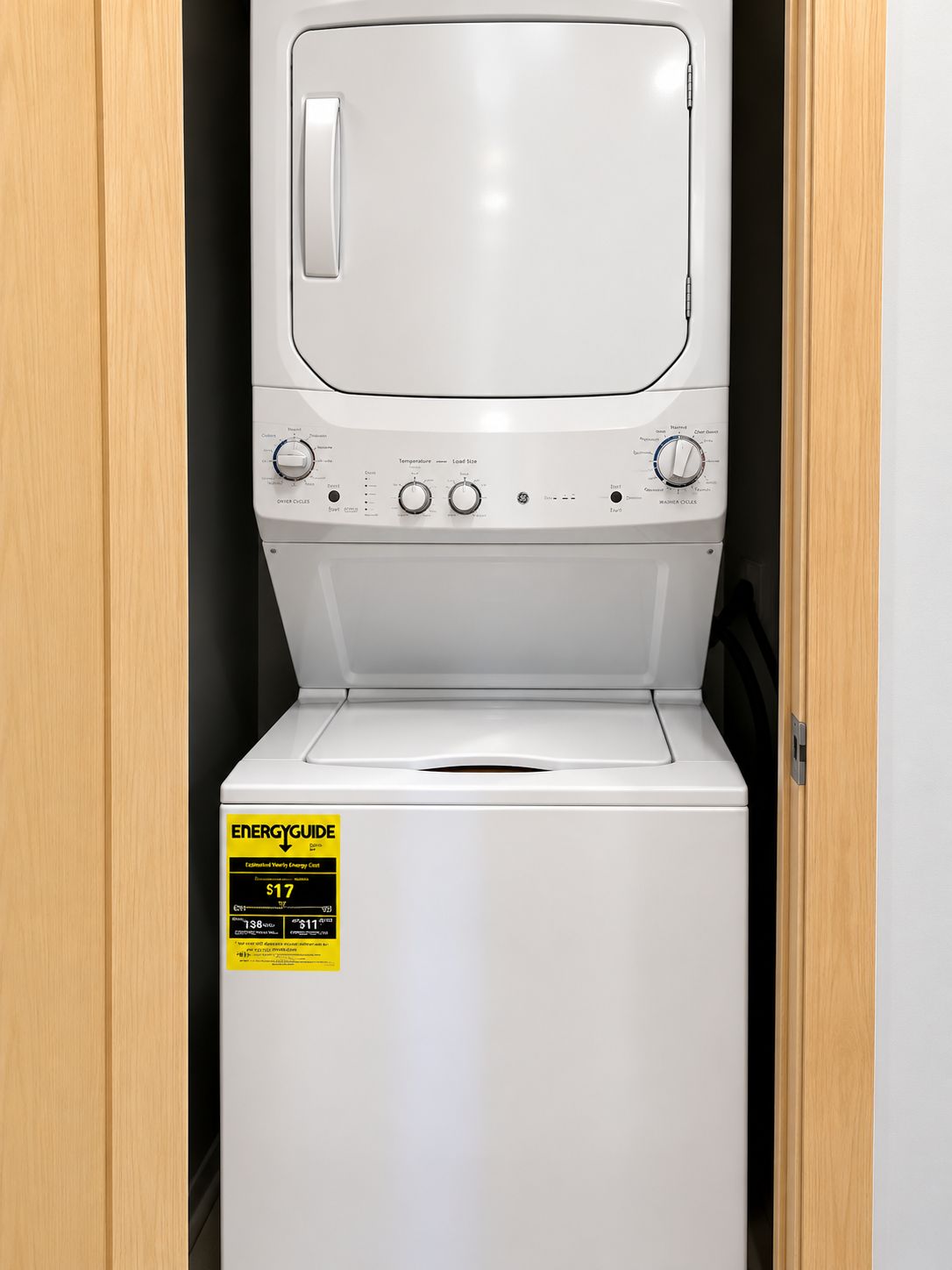 A front view of a white washing machine with a yellow EnergyGuide sticker, placed in a wooden cabinet.