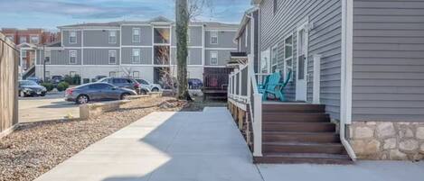 A residential building with a covered porch and a driveway leading to a parking area.
