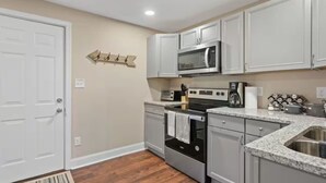 A kitchen with white cabinets, a microwave, a stove, and a sink. - Townhouse near WKU & Mammoth Cave (Bowling Green)