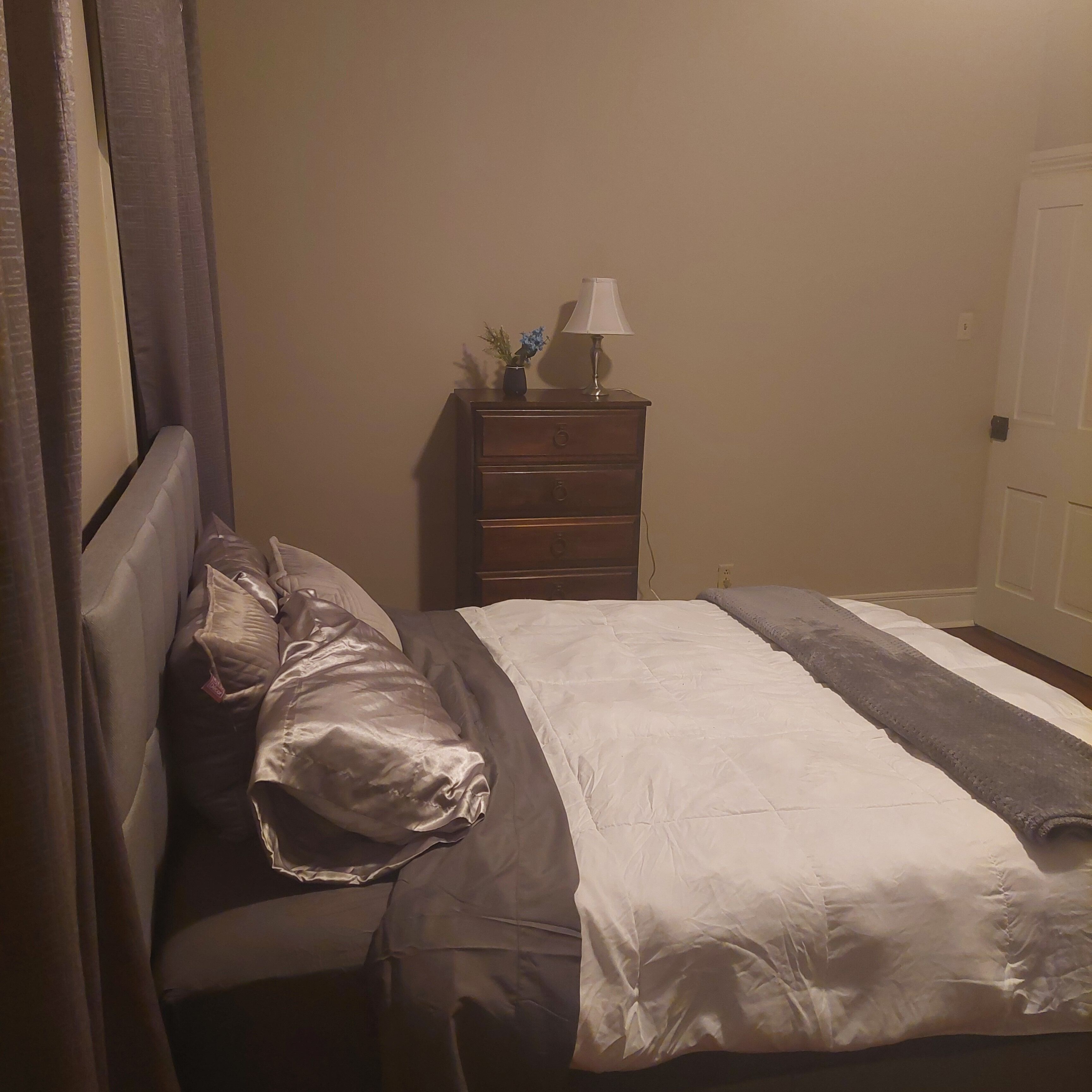 Une chambre à coucher avec un lit, une table de chevet avec une lampe et une commode.