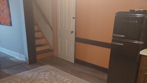 Ett kök med ett svart kylskåp, ett träskåp och en mönstrad matta.