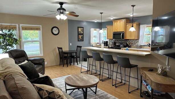 A modern kitchen with a bar area, wooden cabinets, and a dining set. - Custer Cottage / Fenced Yard (Billings)