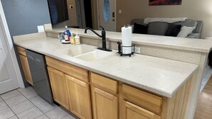 A kitchen with a granite countertop, wooden cabinets, a stainless steel sink, and a dish soap dispenser. - Custer Cottage / Fenced Yard (Billings)
