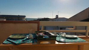 Un balcon avec une table dressée pour un repas, offrant une vue sur le paysage urbain.