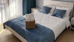 A modern bedroom with a large bed, a bedside table, a hanging light fixture, and a view of the outside through sheer curtains. - Welcoming, cosy 4-bedroom, pet-friendly cottage in Bakuriani (Bakuriani)