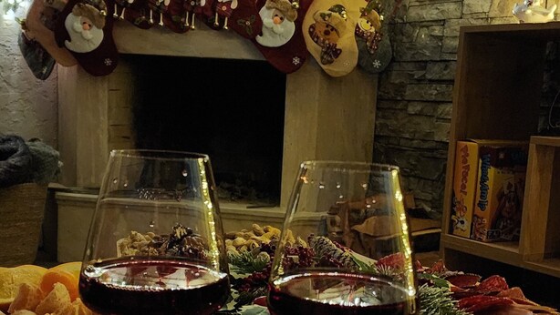 A cozy room with a fireplace, a Christmas tree, and two glasses of red wine on a red tablecloth with 'Merry Christmas' written on it. - Welcoming, cosy 4-bedroom, pet-friendly cottage in Bakuriani (Bakuriani)