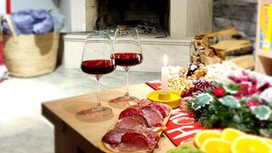 A wooden table with food and drinks, a fireplace with stockings, and a basket in the background. - Welcoming, cosy 4-bedroom, pet-friendly cottage in Bakuriani (Bakuriani)