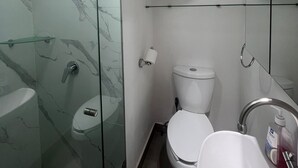 A modern bathroom with a glass-enclosed shower, a toilet, and a sink.