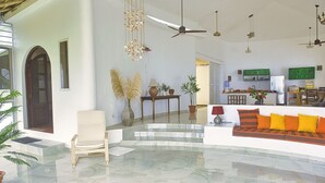 Un grand espace de vie comprenant un canapé, un fauteuil, une table à manger et une cuisine en arrière-plan.