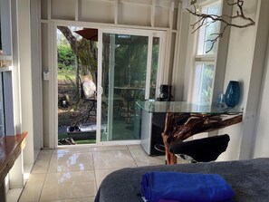 Una habitación con una mesa de vidrio, una silla, una cafetera y vistas al exterior.