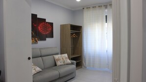 Una sala de estar con un sofá gris, un armario de madera y una obra de arte con forma de corazón rojo en la pared.