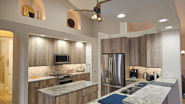 Eine moderne Küche mit Holzschränken, einem Edelstahlkühlschrank und einem eingebauten Backofen.