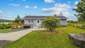 A single-story house with a front porch, a small garden, and a clear sky.