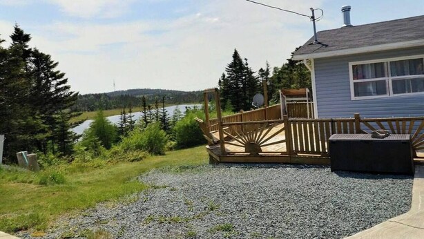 A house with a deck overlooking a lake, surrounded by trees.