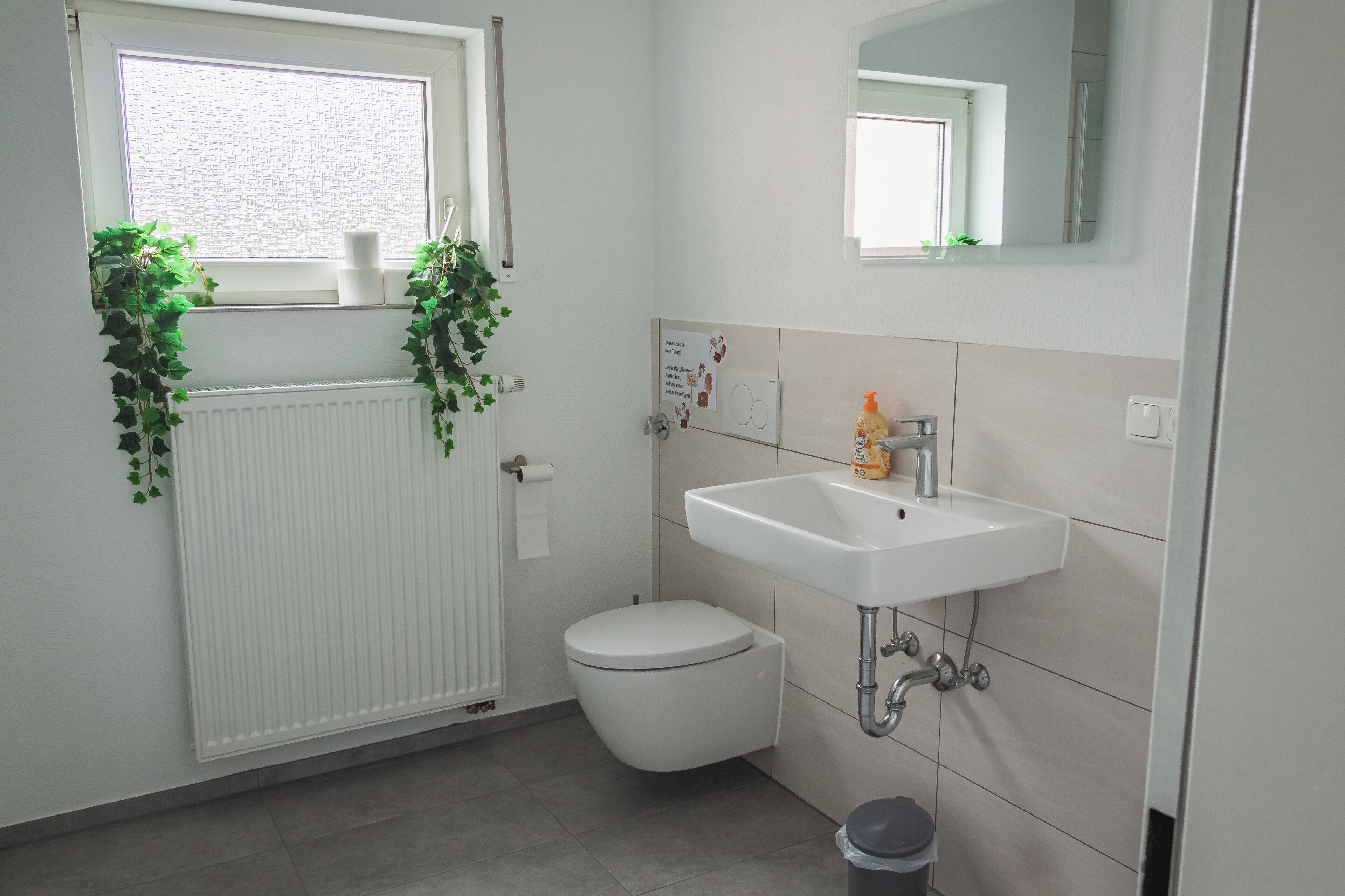 Ein modernes Badezimmer mit Toilette, Waschbecken und Heizkörper.
