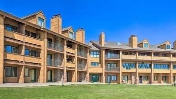 A multi-story hotel with balconies and a green lawn in front. - Cozy Condo, 3 beds, 2 baths, kitchen, near RMNP, Hiking, Golf, Skiing and more! (Granby)