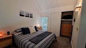 Un dormitorio con cama, mesitas de noche, armario y ventana con persianas.