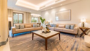 Een moderne woonkamer met twee banken, een salontafel en een groot raam met gordijnen.
