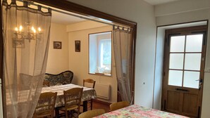 A dining area with a table covered in a floral tablecloth, wooden chairs, and a chandelier. - Gîte des Hautes Côtes de Beaune, former winegrower's residence! <10min from Beaune (Nantoux)
