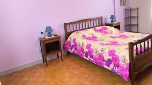 A bedroom with a wooden bed, a nightstand, a lamp, a small table, and a painting on the wall. - Gîte des Hautes Côtes de Beaune, former winegrower's residence! <10min from Beaune (Nantoux)