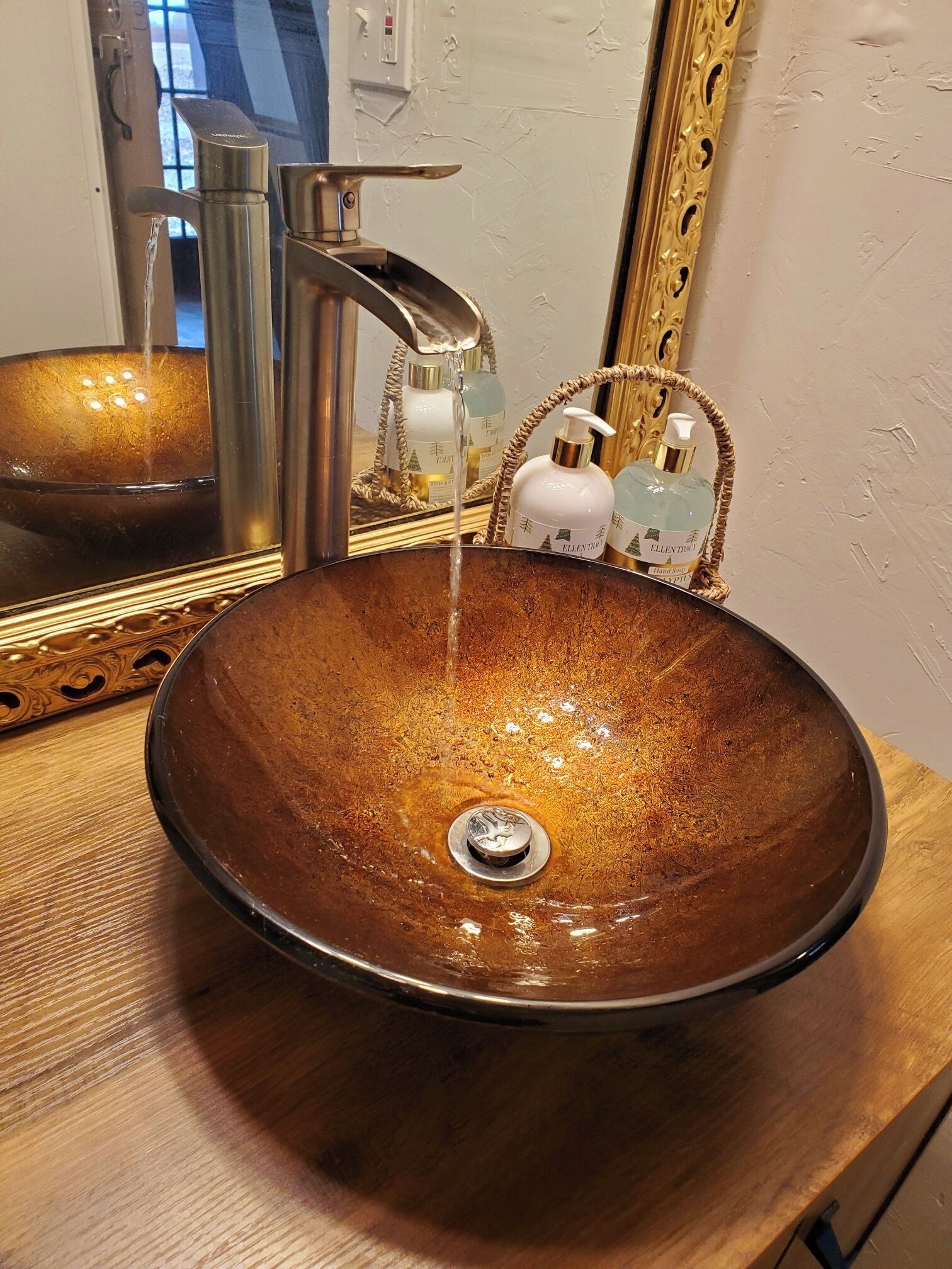 Un évier en céramique marron, doté d’un robinet moderne et d’un miroir avec un cadre décoratif.