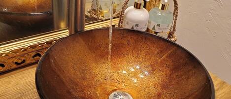 Un évier en céramique marron, doté d’un robinet moderne et d’un miroir avec un cadre décoratif.