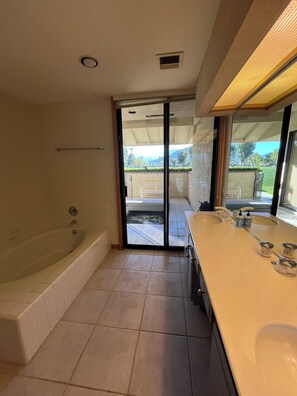 A bathroom with a bathtub, a large sink, and a sliding glass door leading to an outdoor area.