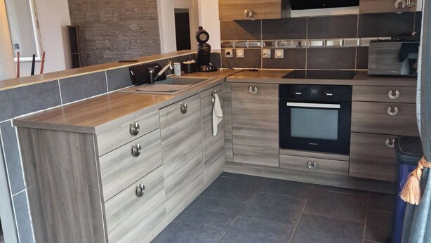 Una cocina moderna con una isla central, electrodomésticos integrados y una pared de acento de piedra.