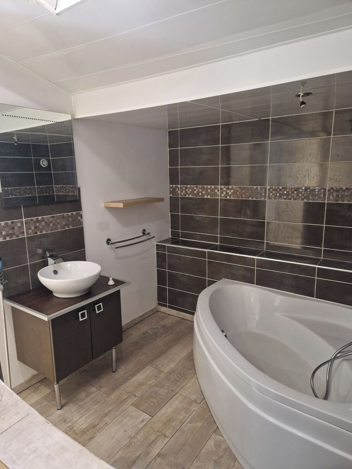 Ein modernes Badezimmer mit einer freistehenden Badewanne, einem weißen Waschbecken und einem Spiegel.