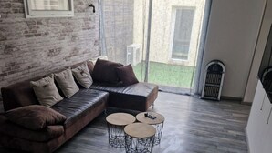 Una sala de estar moderna con un sofá modular, una mesa de centro y una pequeña mesa con tres sillas.