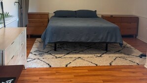A bedroom with a bed, wooden dresser, and a nightstand. There are two paintings on the wall. - 5 Minute Walk to Beach, Restaurants, Shops,Playground. Quaint and Quiet in IRB ! (Indian Rocks Beach)