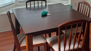 A dining room with a wooden table and chairs, a ceiling fan, and large windows with blinds. - 5 Minute Walk to Beach, Restaurants, Shops,Playground. Quaint and Quiet in IRB ! (Indian Rocks Beach)