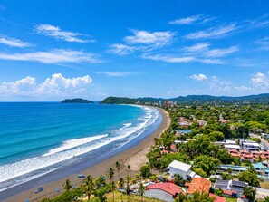 A coastal town with a beach, houses, and a mountainous backdrop.