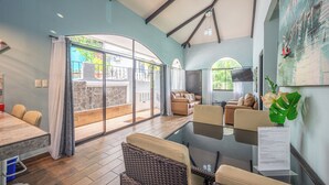 Une pièce spacieuse avec un mur en verre, un coin repas et un espace salon offrant une vue sur l’extérieur.