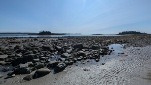 Ein felsiger Strand mit klarem Himmel und ruhigem Wasser.