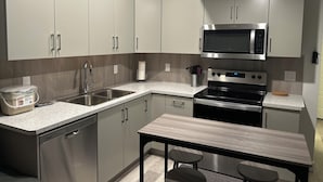 A modern kitchen with stainless steel appliances, a built-in dishwasher, and a granite countertop. - New, spacious and lovely two-bedroom basement suite in a peaceful neighbourhood  (Calgary)