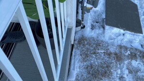 A snow-covered outdoor area with a white metal fence, potted plants, and a snow-covered pathway. - New, spacious and lovely two-bedroom basement suite in a peaceful neighbourhood  (Calgary)