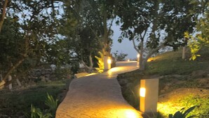 A paved pathway with hexagonal tiles leading through a landscaped area with trees and plants. - Quinta Yaaxbe (Homún)