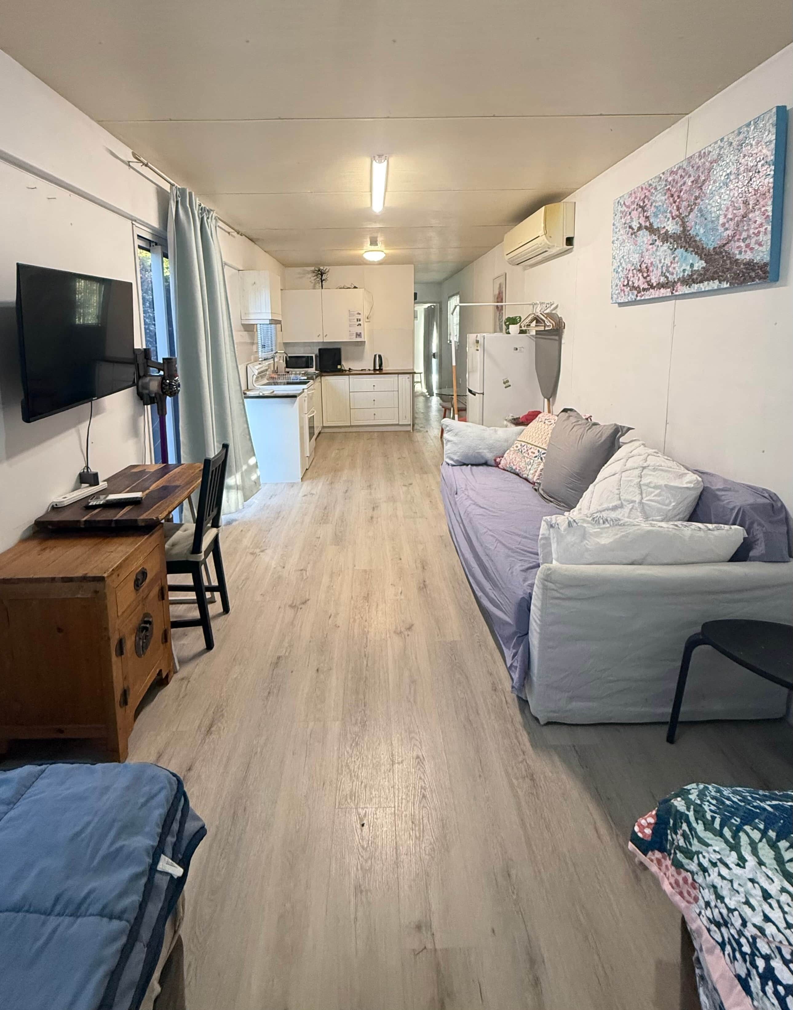 A compact living space with a kitchenette, a sofa, a small table, and a TV.