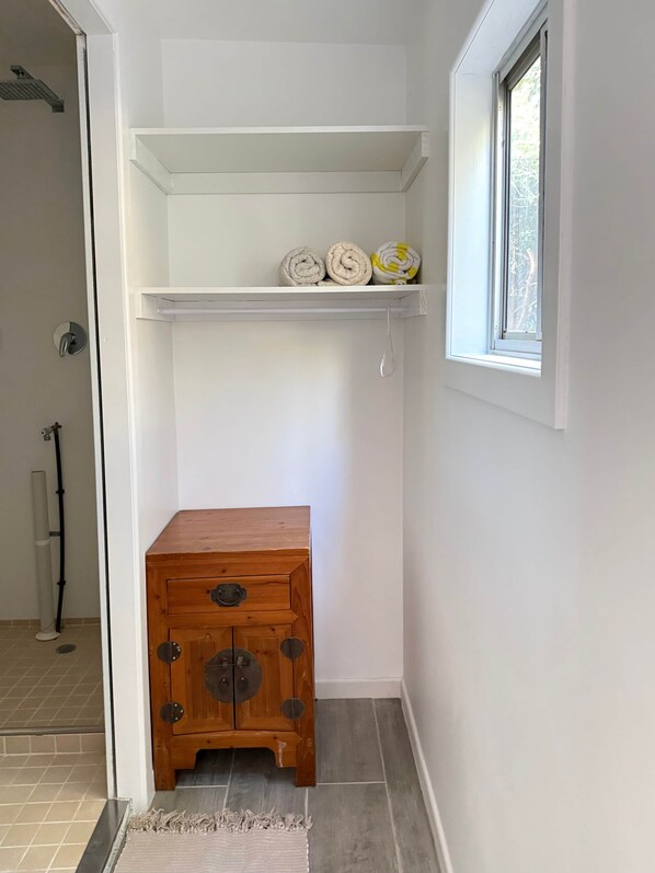 Une salle de bain avec une douche, un porte-serviettes et un meuble en bois.