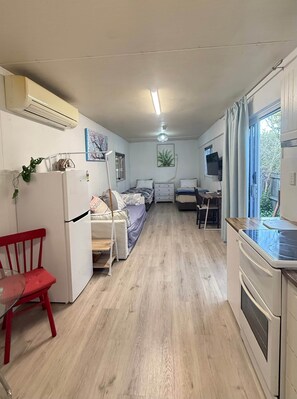 A compact living space with a kitchenette, a dining area, and a bedroom.