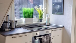 A modern kitchen with a built-in stove, a coffee maker, and a potted plant by the window.