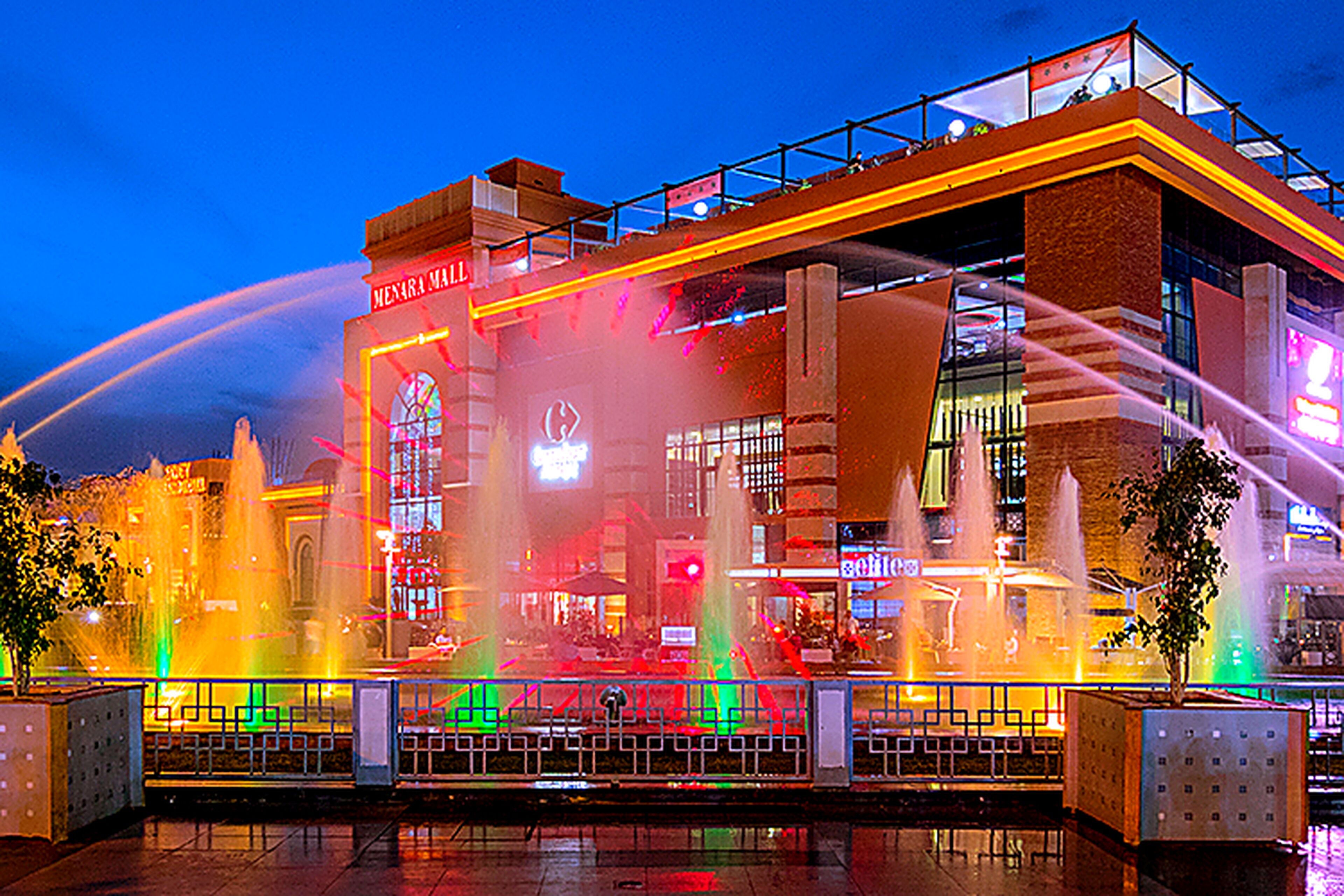 A building with a water fountain display and a sign that reads "MENARA Mall".