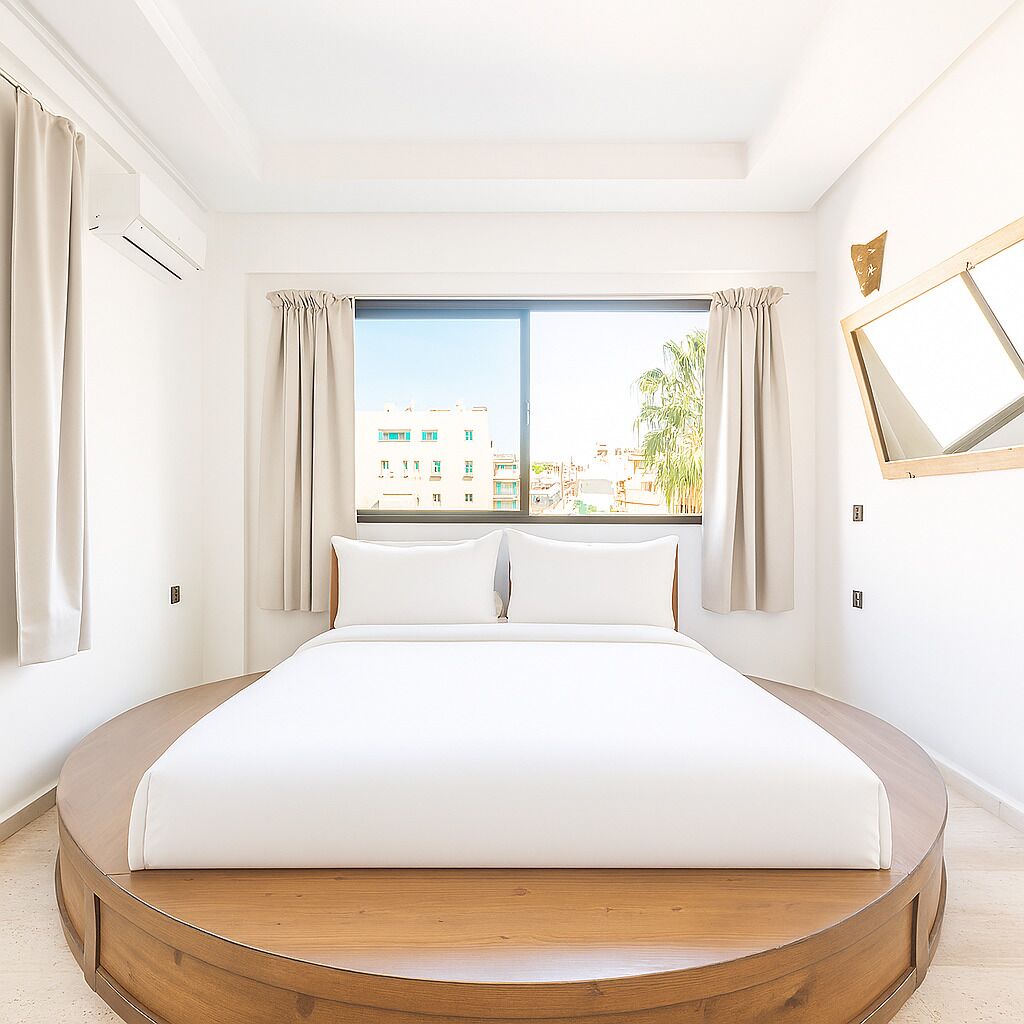 Une chambre d’hôtel moderne avec un grand lit, une fenêtre avec des rideaux et une vue sur les bâtiments environnants.