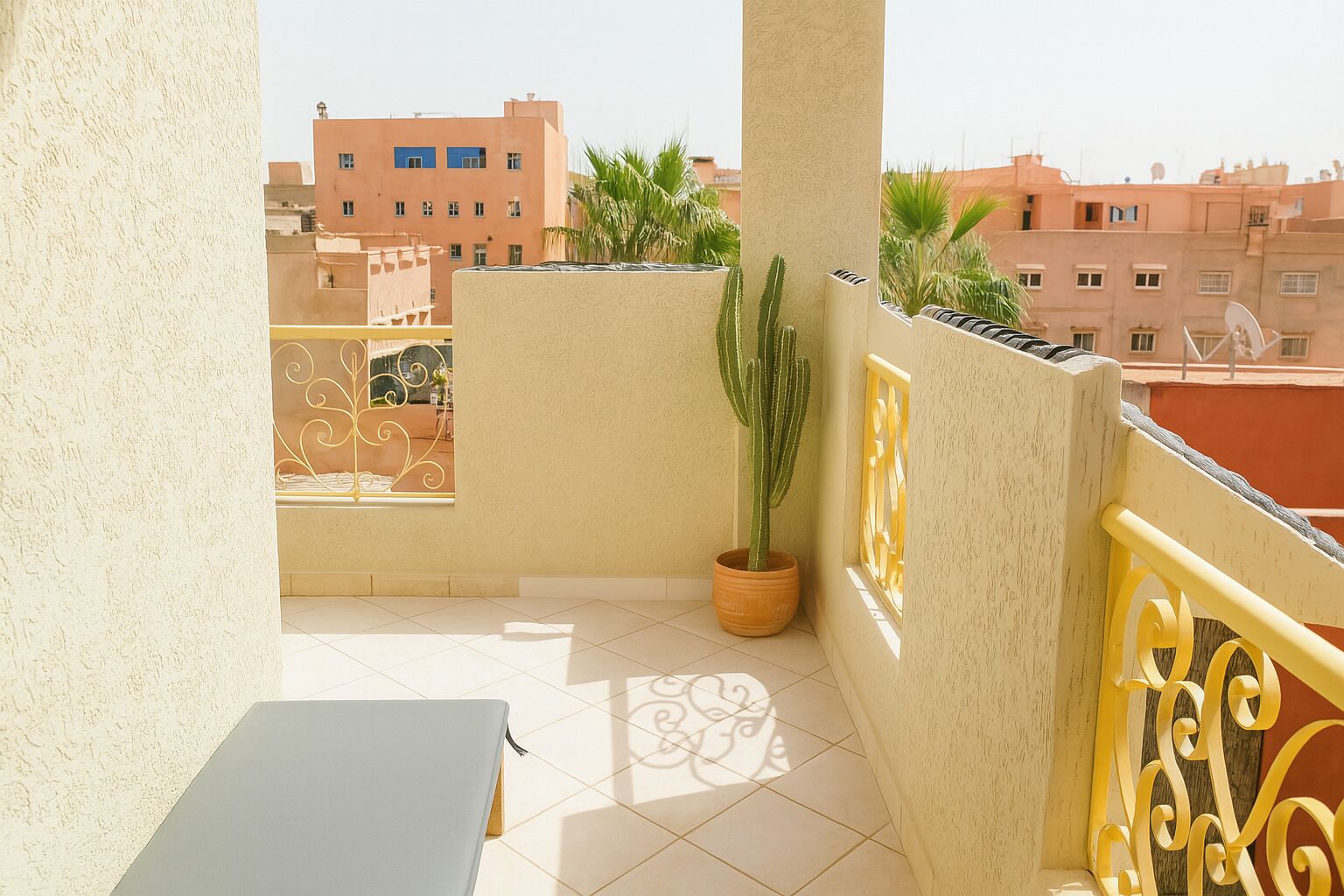 Ein Balkon mit einem Topf als Kakteensubstrat, einem dekorativen Metallgeländer und Blick auf benachbarte Gebäude.