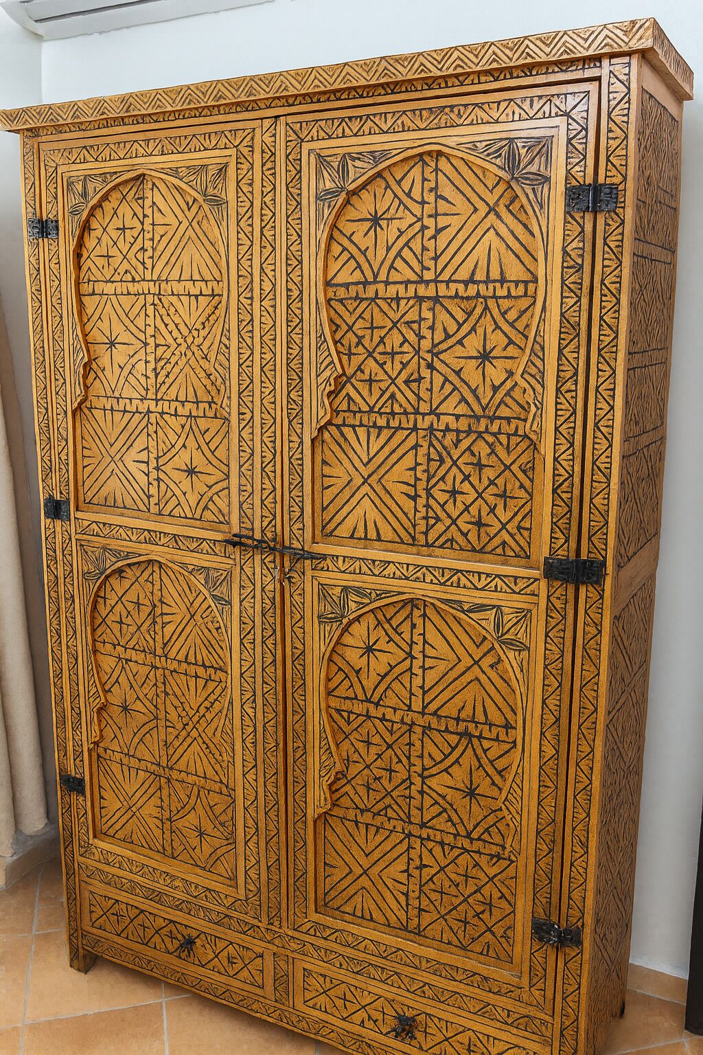 A large, intricately carved wooden cabinet with geometric patterns and a central arched design.