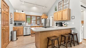 A modern kitchen with wooden cabinets, stainless steel appliances, and a central island with stools.